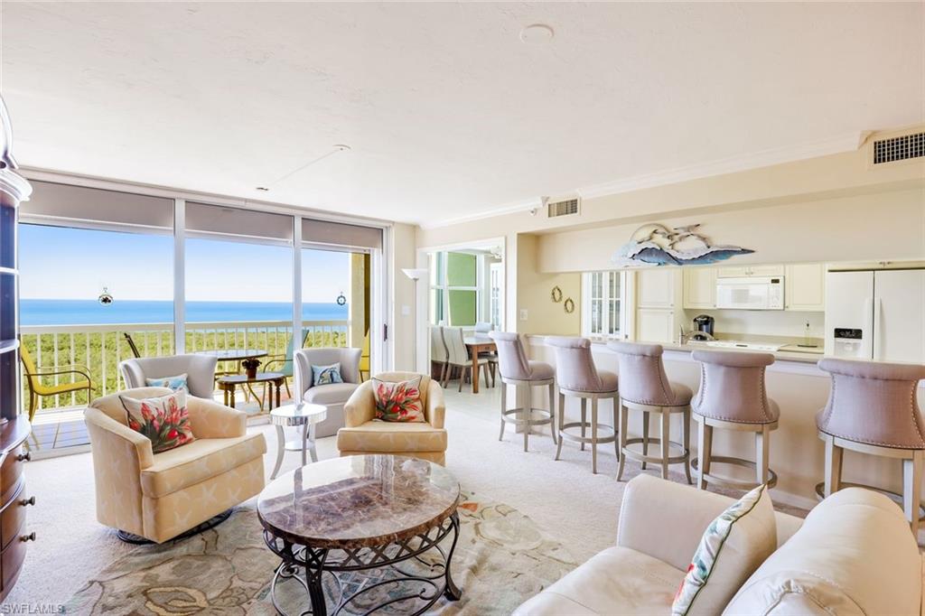 Living room featuring floor to ceiling windows, a water view, light carpet, and crown molding