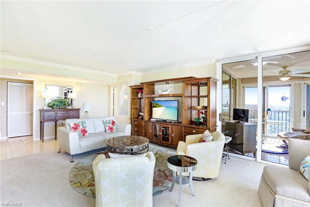 Living room with a ceiling fan, plenty of natural light, light colored carpet, and crown molding