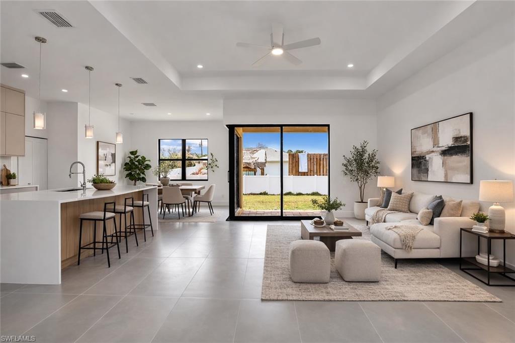 Living room featuring a raised ceiling and ceiling fan. This photo was digitally staged.
