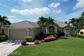Ranch-style home with a front yard, an attached garage, and driveway