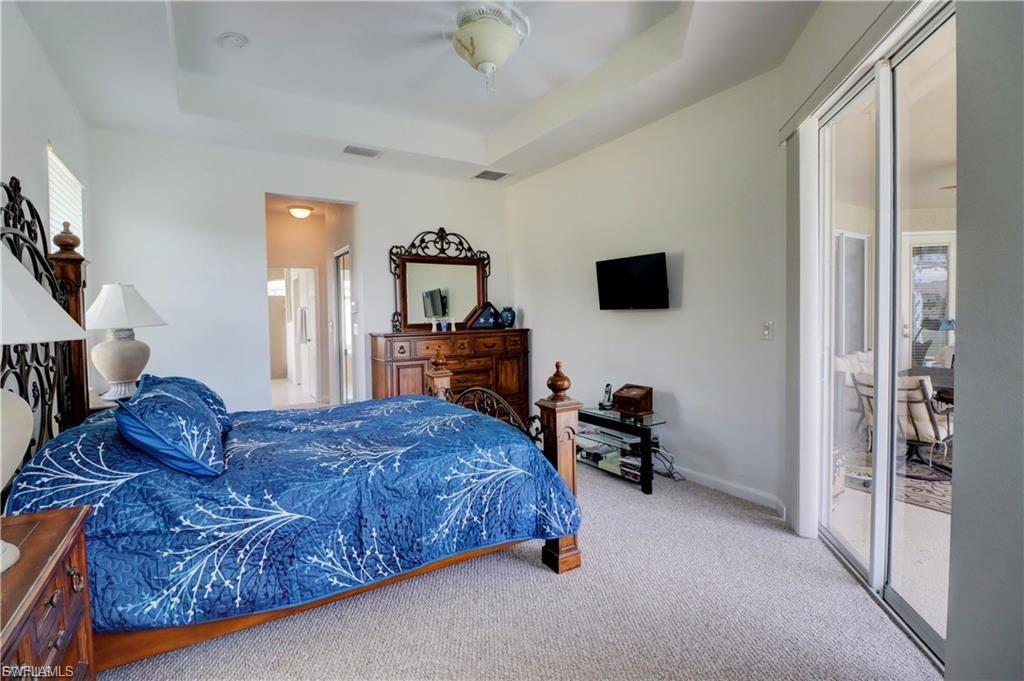Bedroom with access to outside, light carpet, a ceiling fan, and a raised ceiling