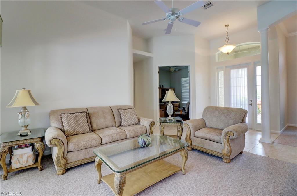 Living room featuring ornate columns, a ceiling fan, and tile patterned flooring