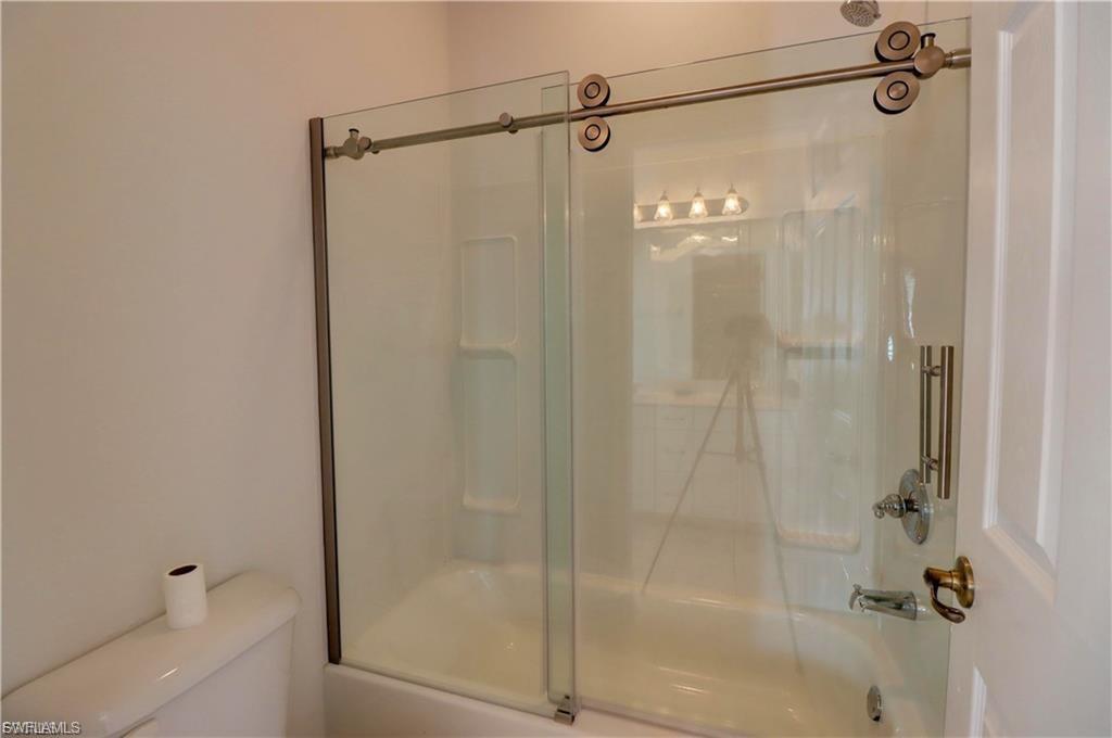 Full bathroom with toilet and bath / shower combo with glass door
