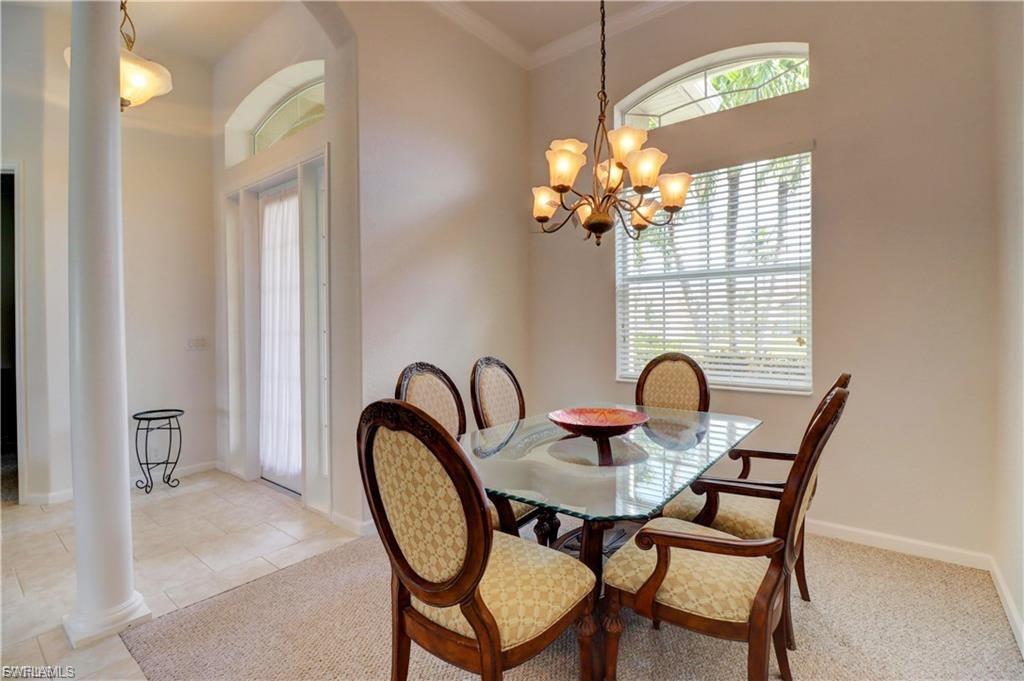 Dining area featuring crown molding, decorative columns, and suspended lighting