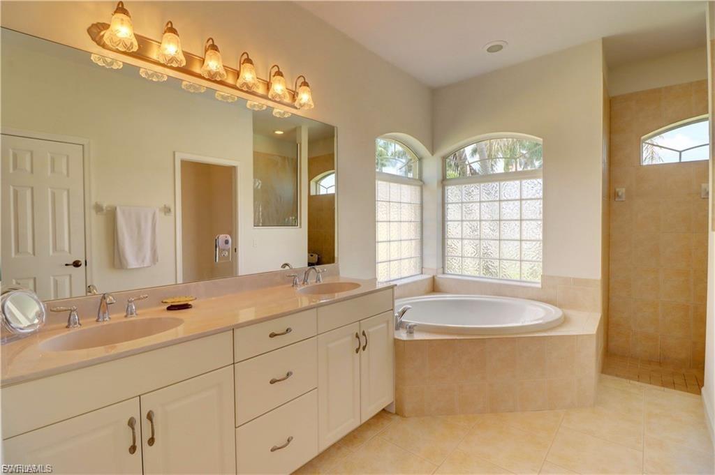 Full bathroom with double vanity, a garden tub, a walk in shower, and light tile patterned floors