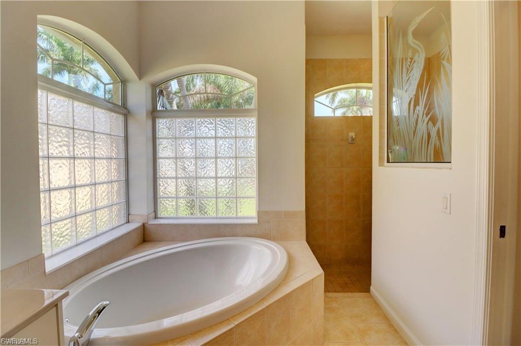 Full bath with walk in shower, a garden tub, and light tile patterned flooring