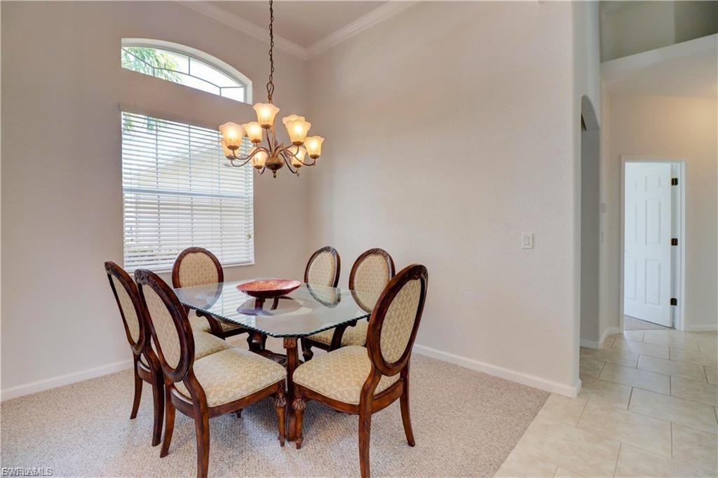 Dining room with ornamental molding, a chandelier, and light tile patterned flooring