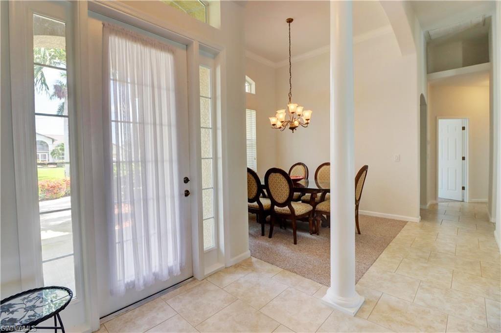 Entryway featuring ornamental molding, suspended lighting, light tile patterned flooring, light colored carpet, and arched walkways