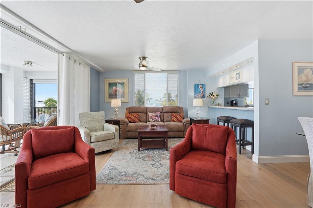 Living area featuring ceiling fan, light wood finished floors, and a textured ceiling - Virtually Edited Image