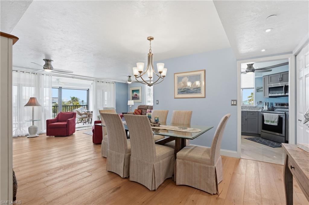 Dining room featuring ceiling fan, light wood-style floors, and plenty of natural light - Virtually Edited Image