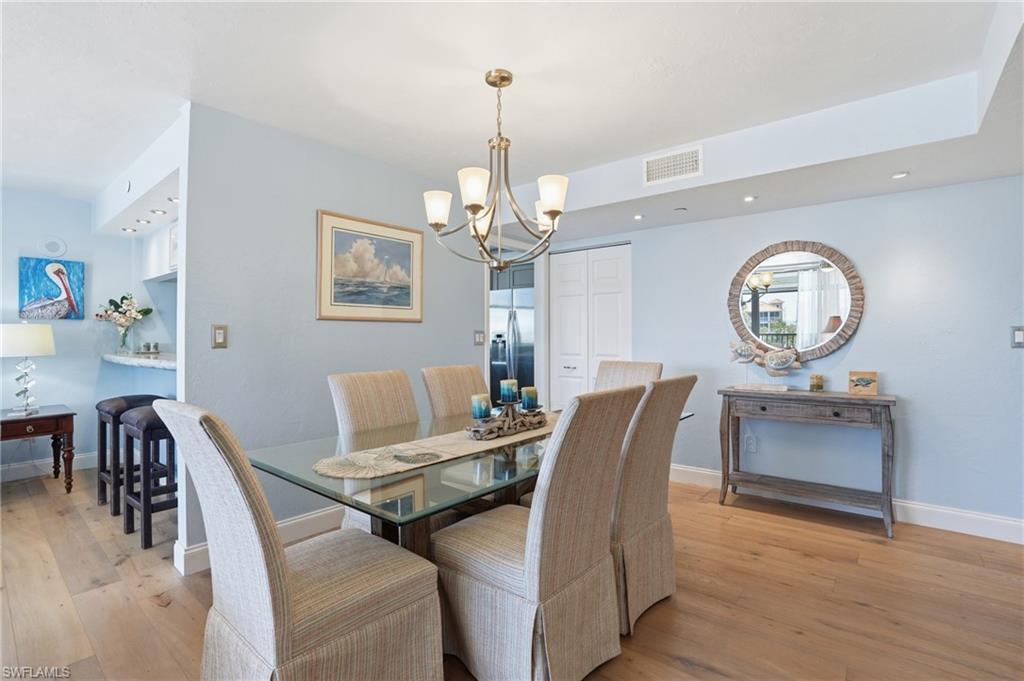 Dining room featuring light wood-type flooring and suspended lighting - Virtually Edited Image