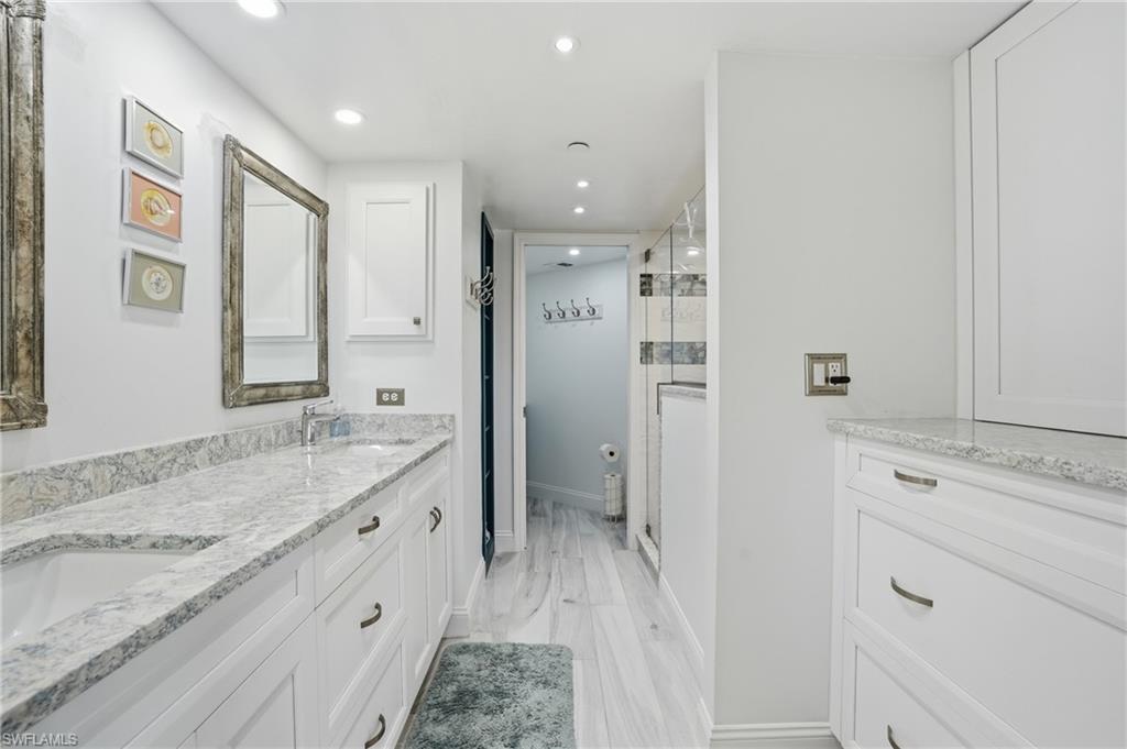 Full bath with double vanity, recessed lighting, a shower stall, and light wood finished floors - Virtually Edited Image