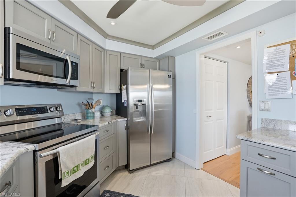 Kitchen with gray cabinetry, stainless steel appliances, light stone counters, and recessed lighting - Virtually Edited Image