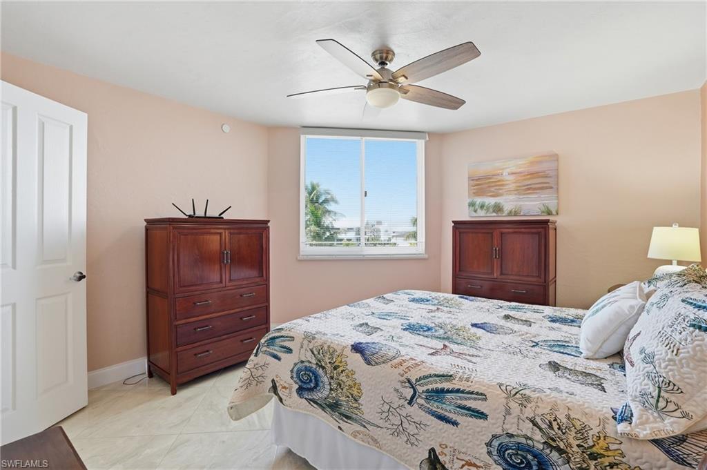 Bedroom with ceiling fan and light tile patterned floors - Virtually Edited Image