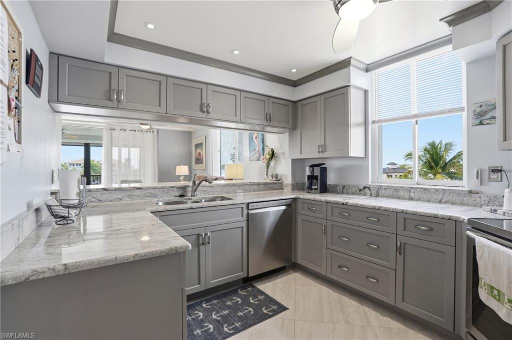 Kitchen with gray cabinets, light stone counters, dishwasher, recessed lighting, and a ceiling fan - Virtually Edited Image
