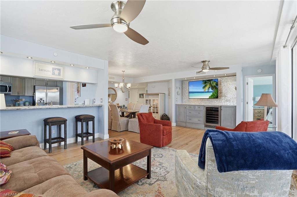 Living room featuring light wood finished floors, hanging lights, and ceiling fan - Virtually Edited Image