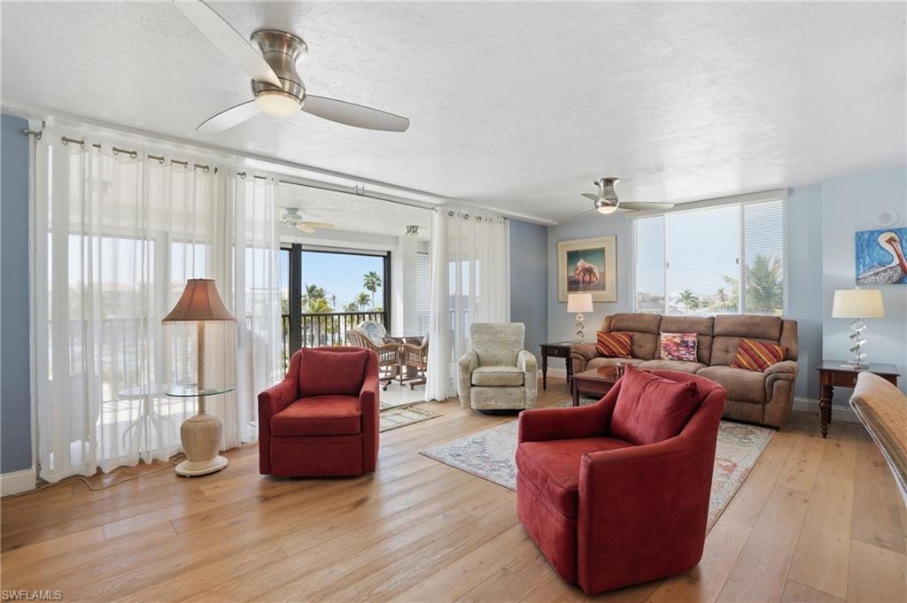 Living area featuring light wood-type flooring, a ceiling fan, and a textured ceiling - Virtually Edited Image