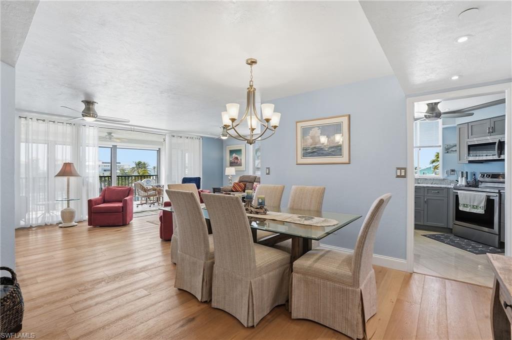 Dining area with ceiling fan, light wood-style floors, and a chandelier - Virtually Edited Image