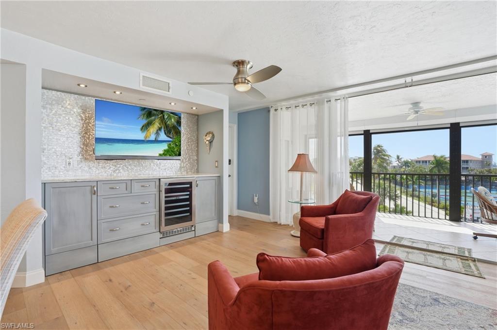 Living room with ceiling fan, beverage cooler, and light wood-type flooring - Virtually Edited Image
