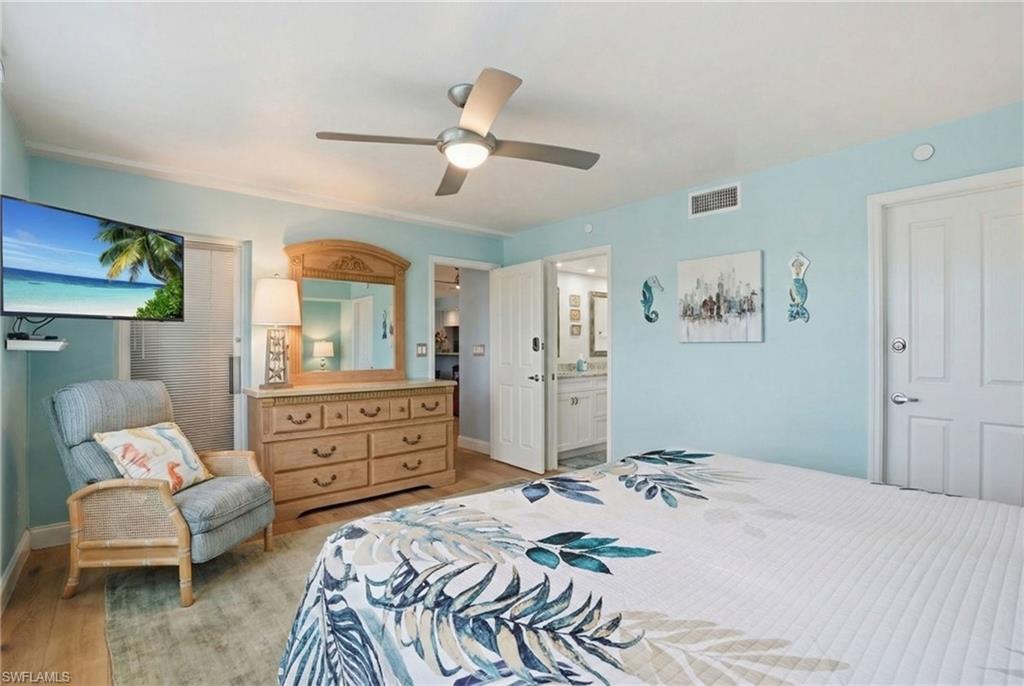 Bedroom featuring light wood-style flooring, a ceiling fan, and ensuite bathroom - Virtually Edited Image