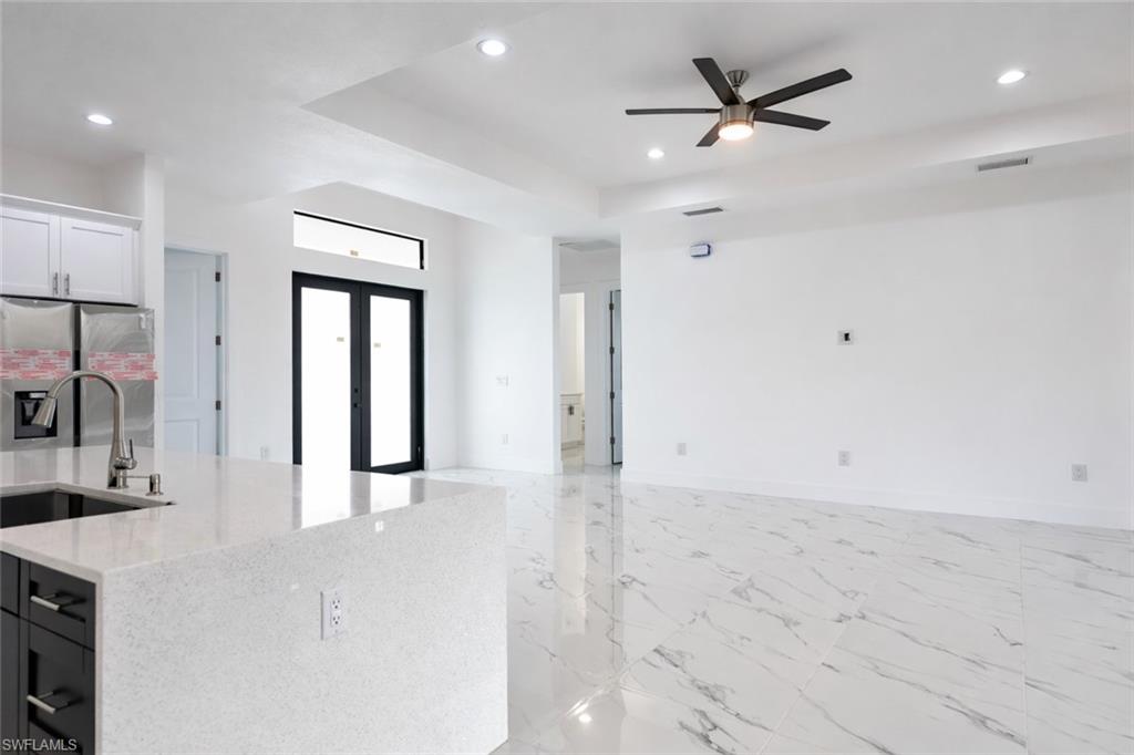 Kitchen featuring stainless steel refrigerator with ice dispenser, light stone countertops, light marble finish flooring, ceiling fan, and french doors