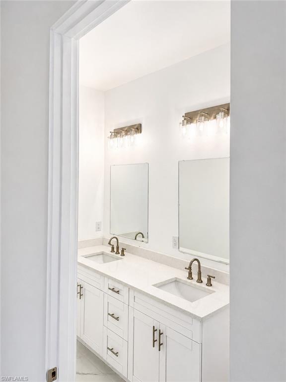 Junior Suite Double vanity featuring white shaker cabinetry, integrated rectangular sinks, and brushed bronze fixtures