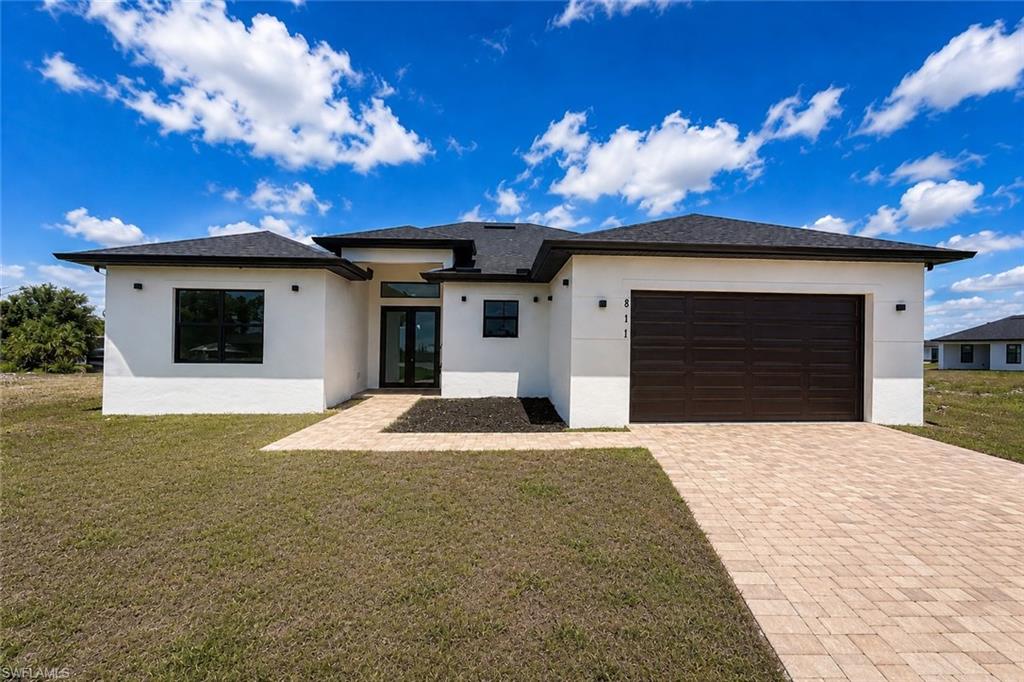 Modern stucco exterior with black-framed windows and a dark brown garage door
