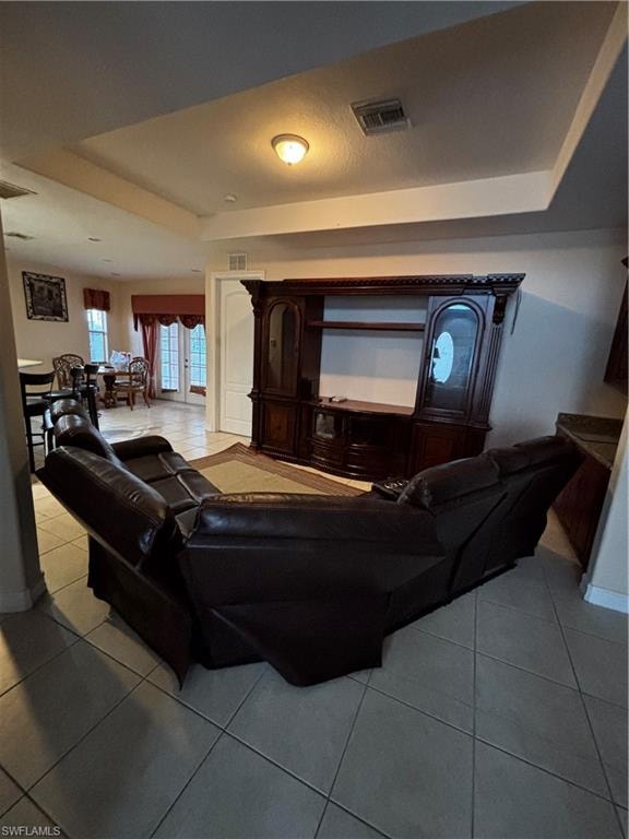 Living area with light tile patterned flooring and a raised ceiling