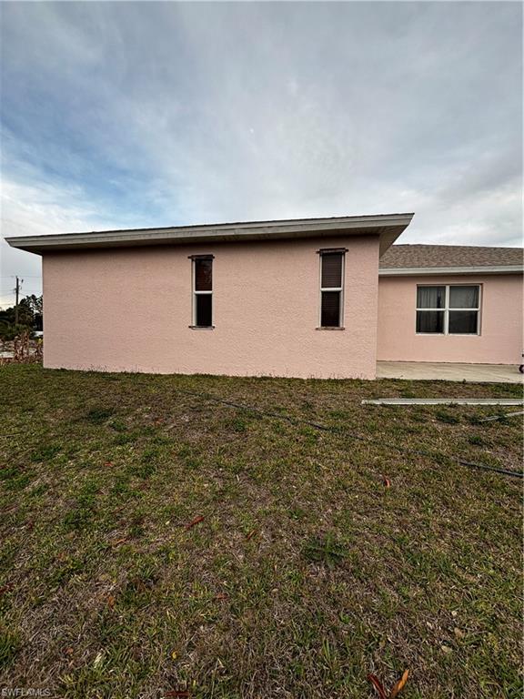 View of property exterior with a lawn and stucco siding