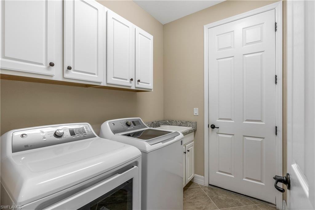Laundry area featuring washer and clothes dryer, light tile patterned floors, and cabinet space