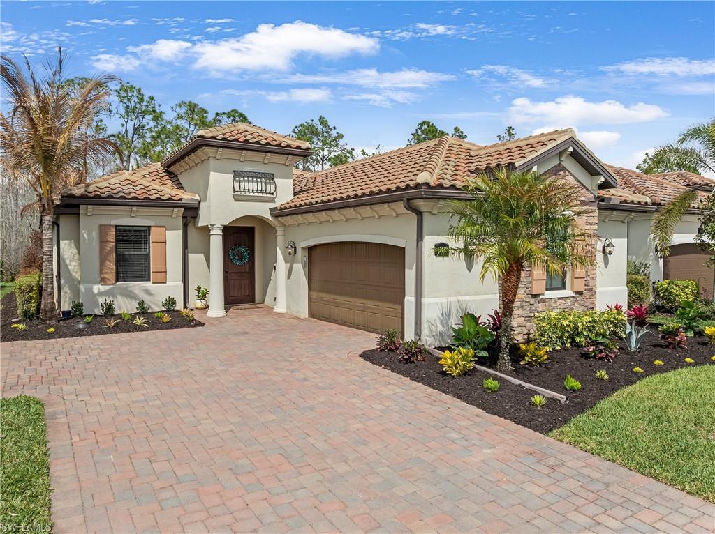 Mediterranean / spanish-style home featuring an attached garage, stucco siding, decorative driveway, stone siding, and a tiled roof