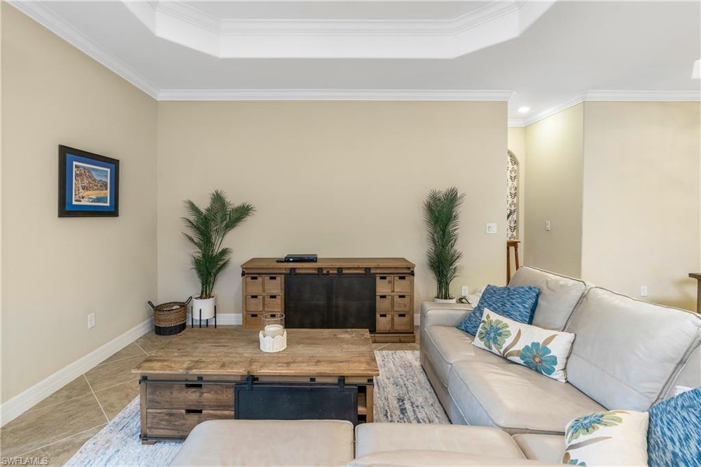 Tiled living area featuring crown molding and a tray ceiling
