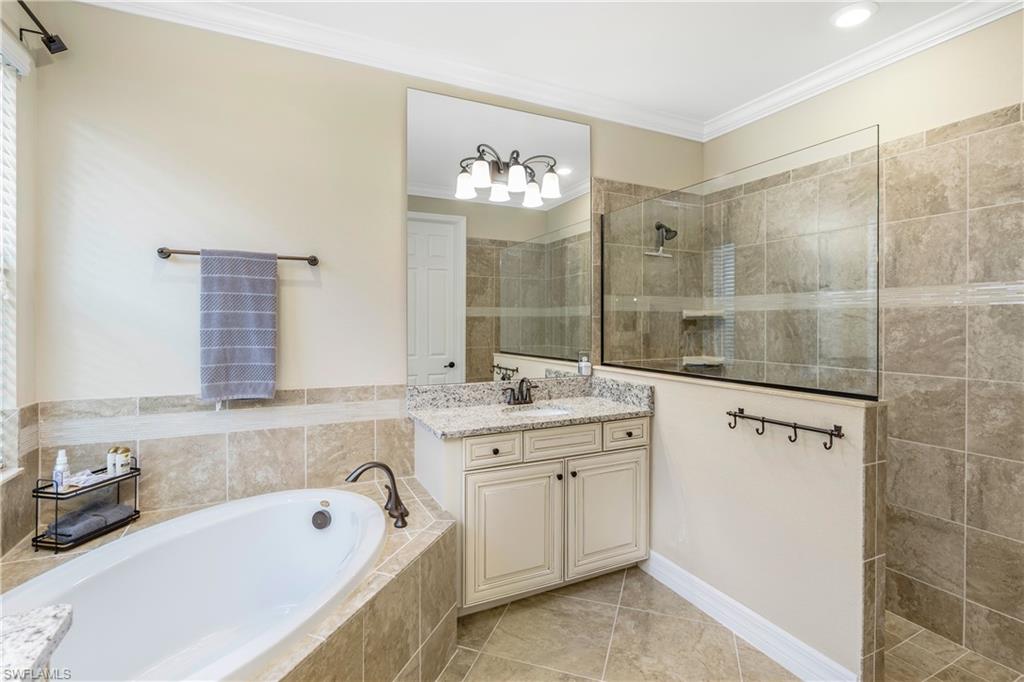 Bathroom featuring vanity, ornamental molding, walk in shower, a garden tub, and light tile patterned floors