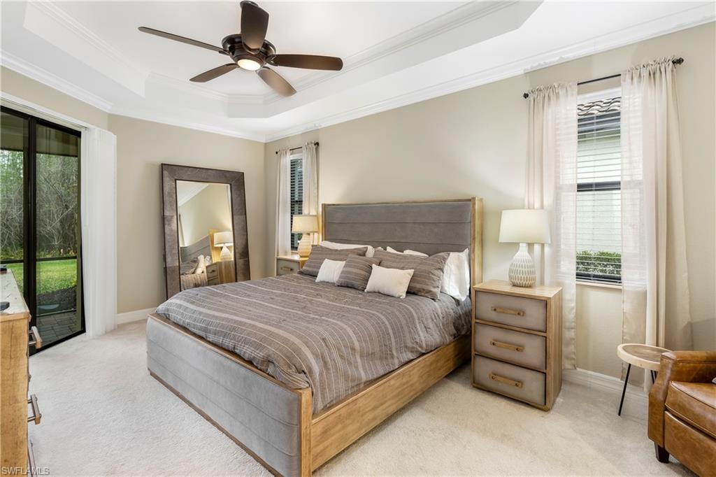 Bedroom featuring access to exterior, light colored carpet, crown molding, a tray ceiling, and a ceiling fan