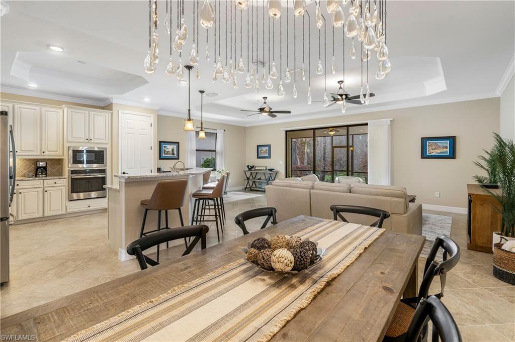 Dining room featuring a raised ceiling, ornamental molding, a ceiling fan, and light tile patterned floors
