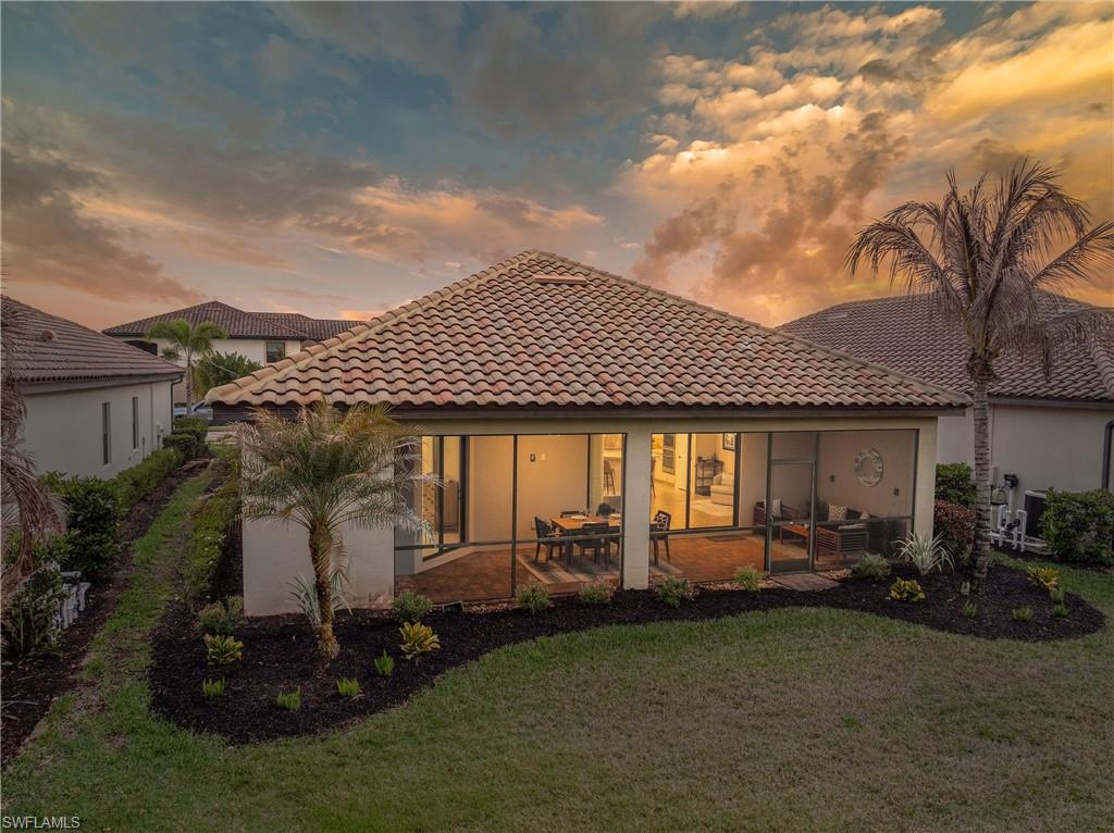 Back of property featuring a tiled roof, a patio, stucco siding, and a yard