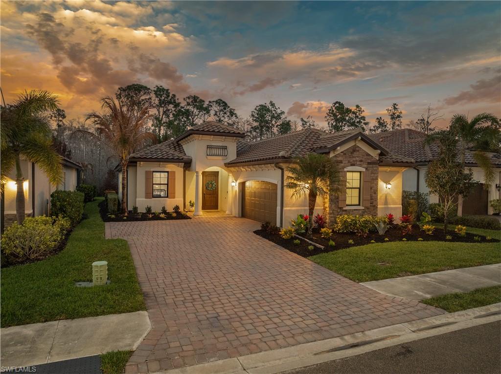 Mediterranean / spanish-style house featuring an attached garage, a yard, decorative driveway, stucco siding, and a tile roof
