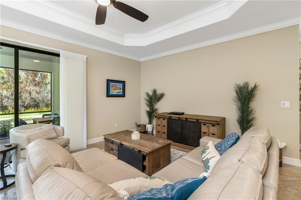 Living area with ornamental molding, a ceiling fan, and a tray ceiling