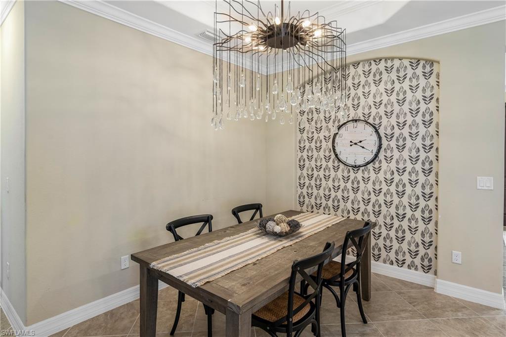 Dining space with suspended lighting, ornamental molding, and light tile patterned floors
