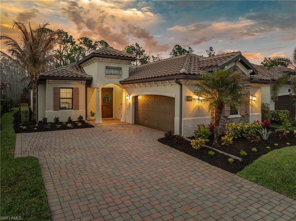 Mediterranean / spanish home with a garage, decorative driveway, stucco siding, and a tile roof