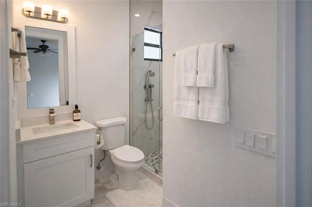 Full bathroom featuring vanity, a marble finish shower, and a ceiling fan