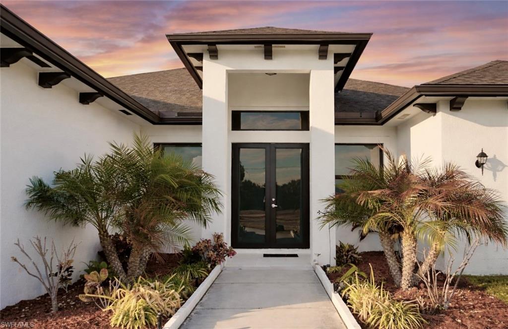 Exterior entry at dusk featuring roof with shingles, french doors, and stucco siding