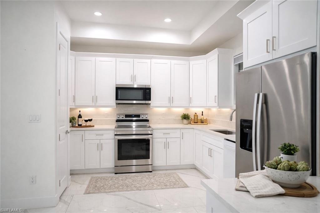 Kitchen featuring stainless steel appliances, white cabinets, light marble finish floors, recessed lighting, and light stone countertops