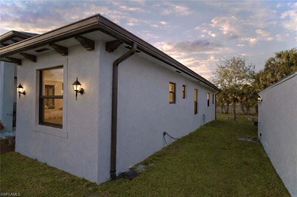View of side of home featuring stucco siding and a yard