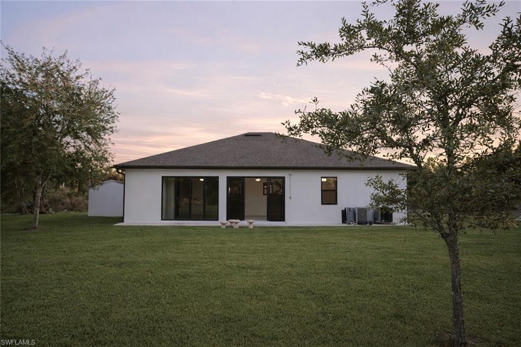 Back of house featuring a lawn, a patio, and stucco siding