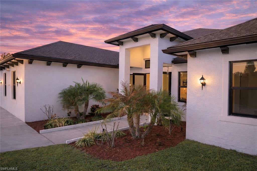 View of home's exterior with stucco siding, a yard, and roof with shingles