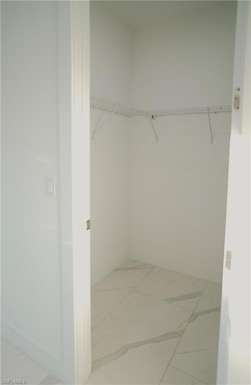 Walk in closet with light marble finish flooring