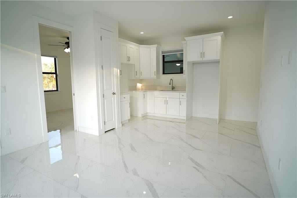 Kitchen featuring white cabinets, recessed lighting, light countertops, ceiling fan, and light marble finish floors