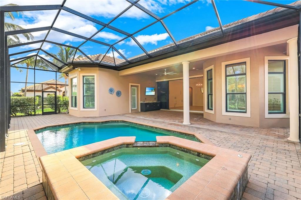 Combined pool / hot tub featuring a patio area, a sunroom, and glass enclosure