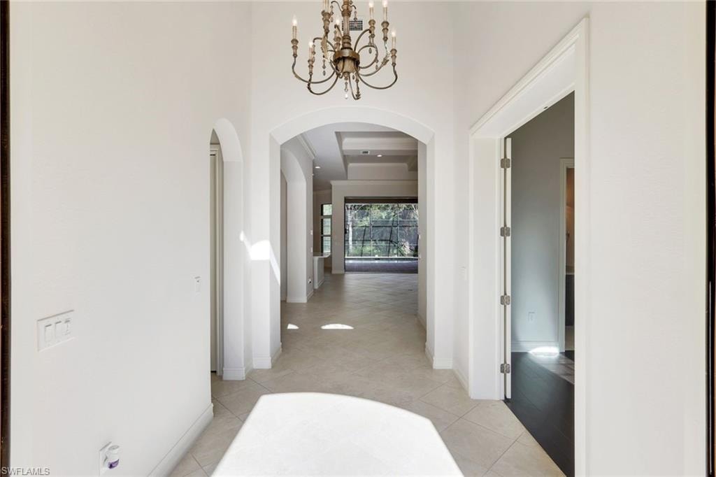 Hallway with arched walkways, suspended lighting, a high ceiling, and light tile patterned floors